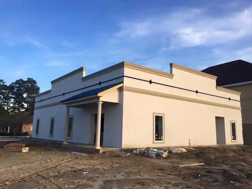 A white building with a blue roof is under construction.