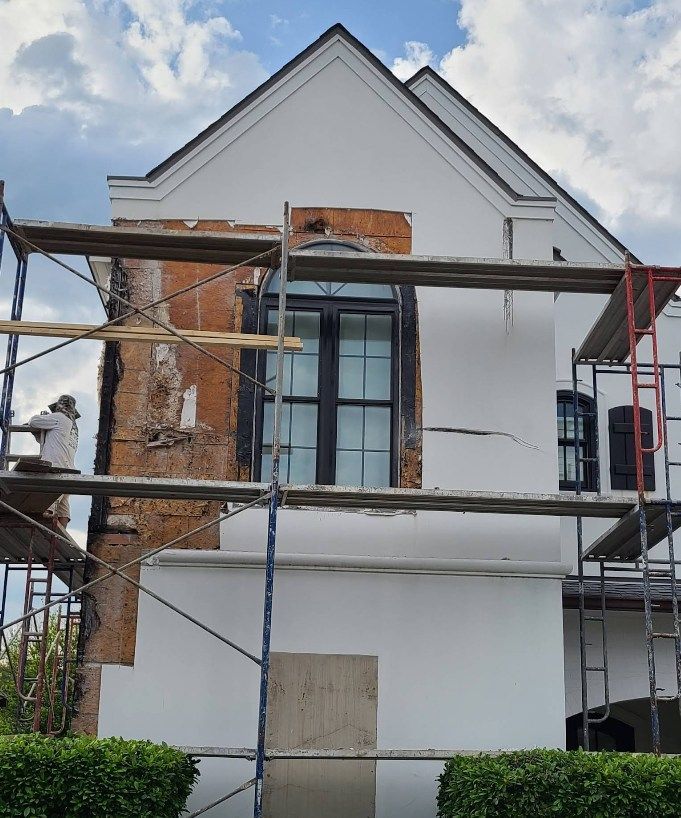 A white house is being painted with scaffolding around it.