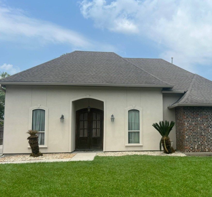 A white house with a gray roof and a palm tree in front of it.