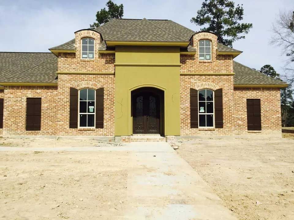 A brick house with a green trim and brown shutters.