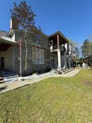 A large house is being painted on a sunny day.