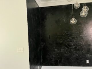 A room with a black wall and a ceiling light hanging from it.