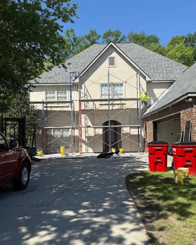 A car is parked in front of a house that is being painted.