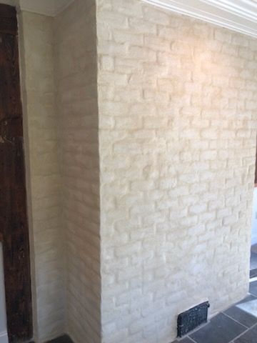 A room with a white brick wall and a fireplace.