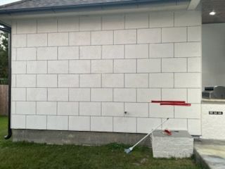 A white brick wall with a broom in front of it.