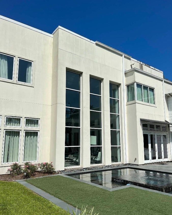 A large white house with a pool in front of it.