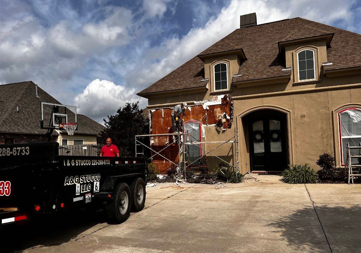 A dumpster is parked in front of a house that is being painted.