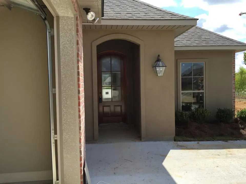 The front door of a house with a garage door open.