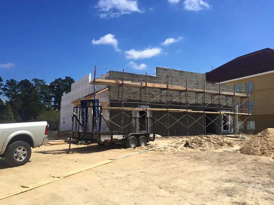 A white truck is parked in front of a building under construction.