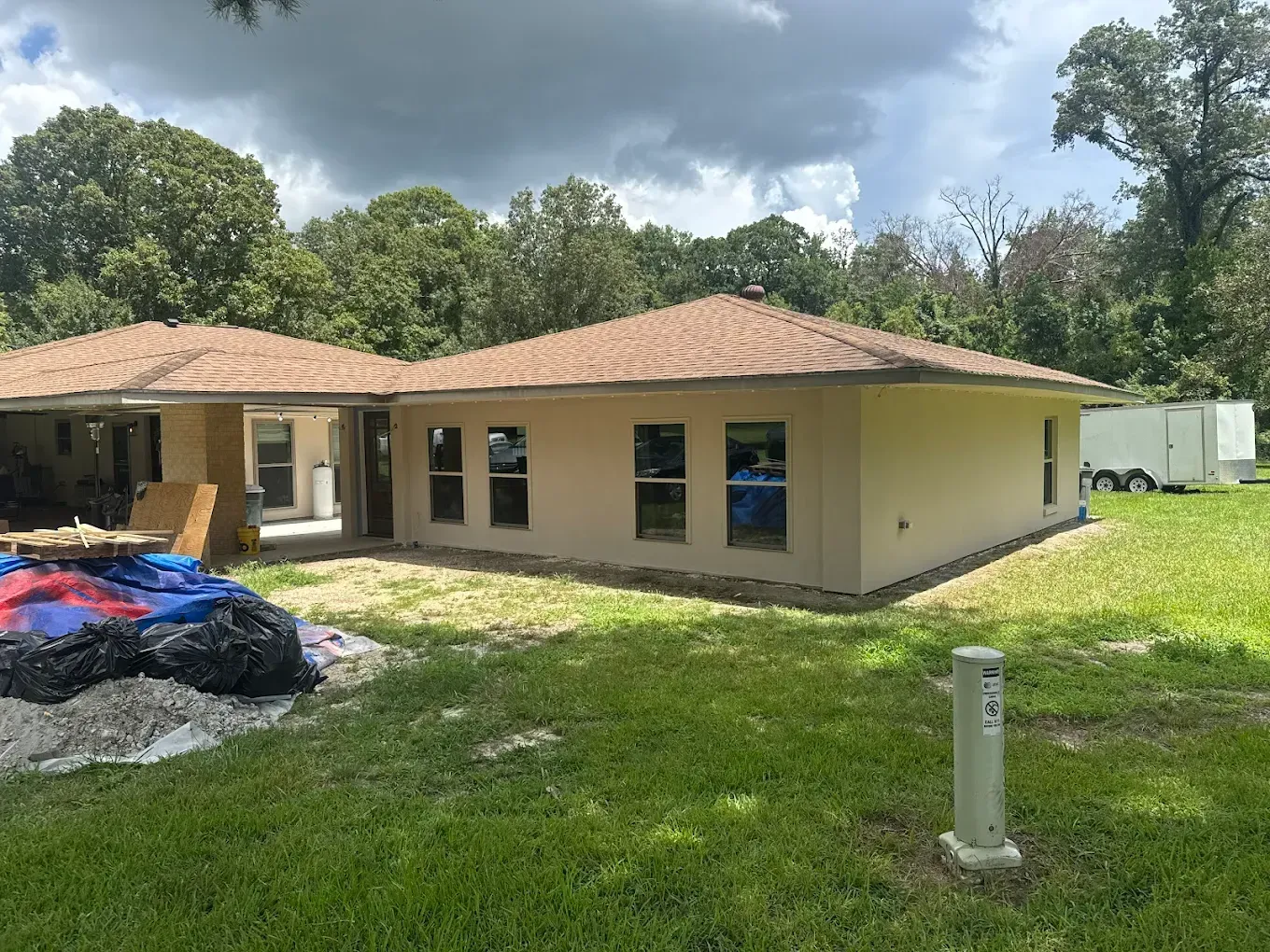 Tan house under construction with brown roof, windows, and green yard.