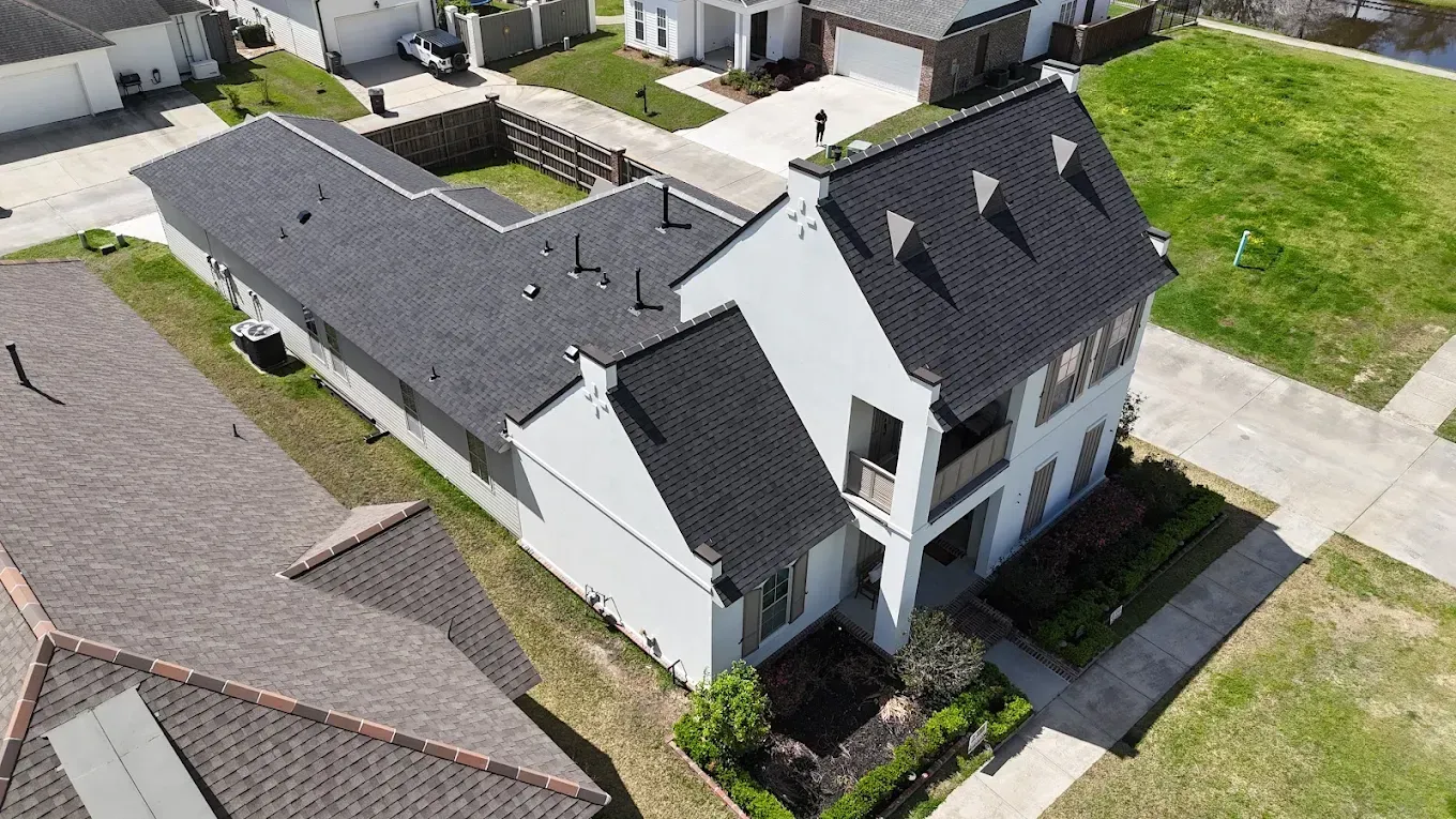 Aerial view of a two-story white house with a black roof and a green lawn.