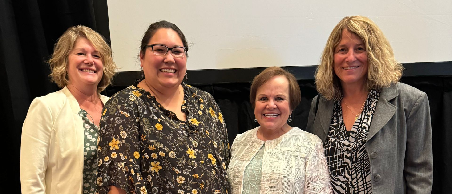 A group of four women are standing next to each other and smiling — Homer, AK — Preventive Dentistry Services