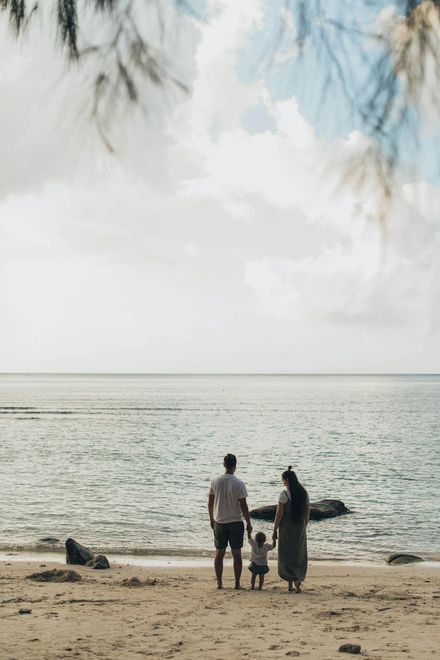 A family is standing on a beach looking at the ocean.