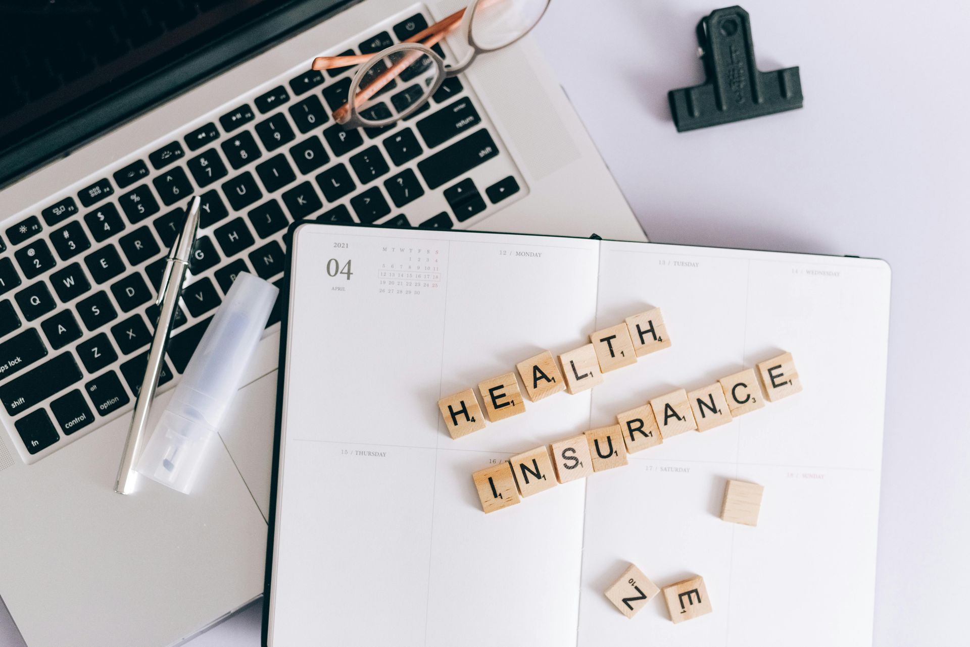 A notebook with the words `` health insurance '' written on it next to a laptop.