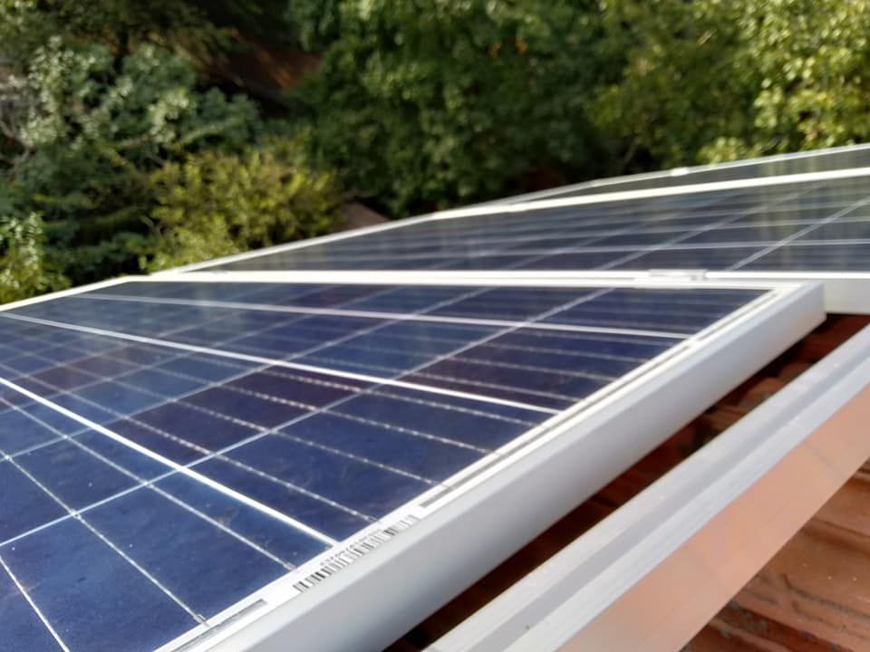 Pannelli solari su un tetto, con uno sfondo di alberi verdi.