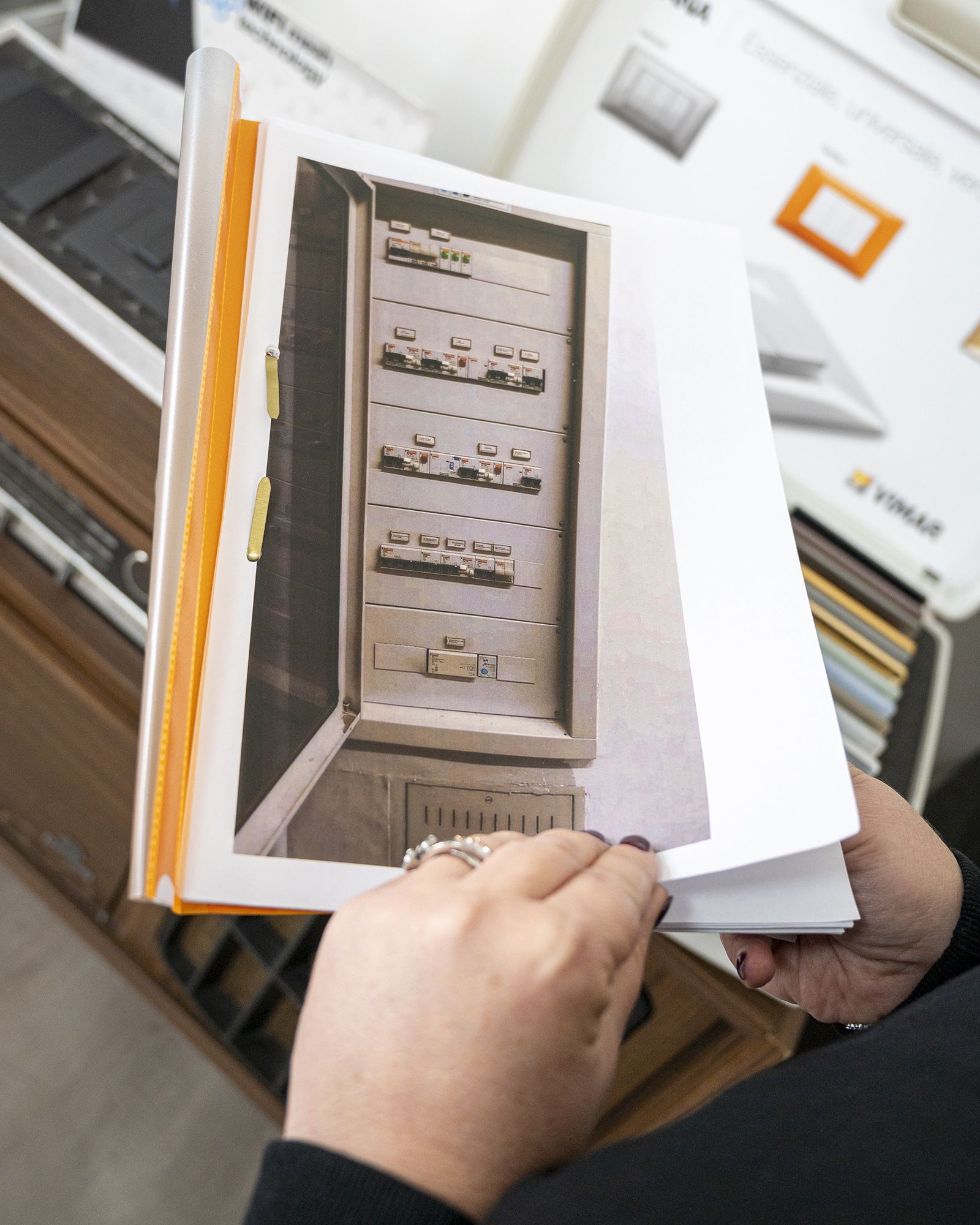 Persona che tiene un libro aperto su una pagina con la foto di un quadro elettrico.