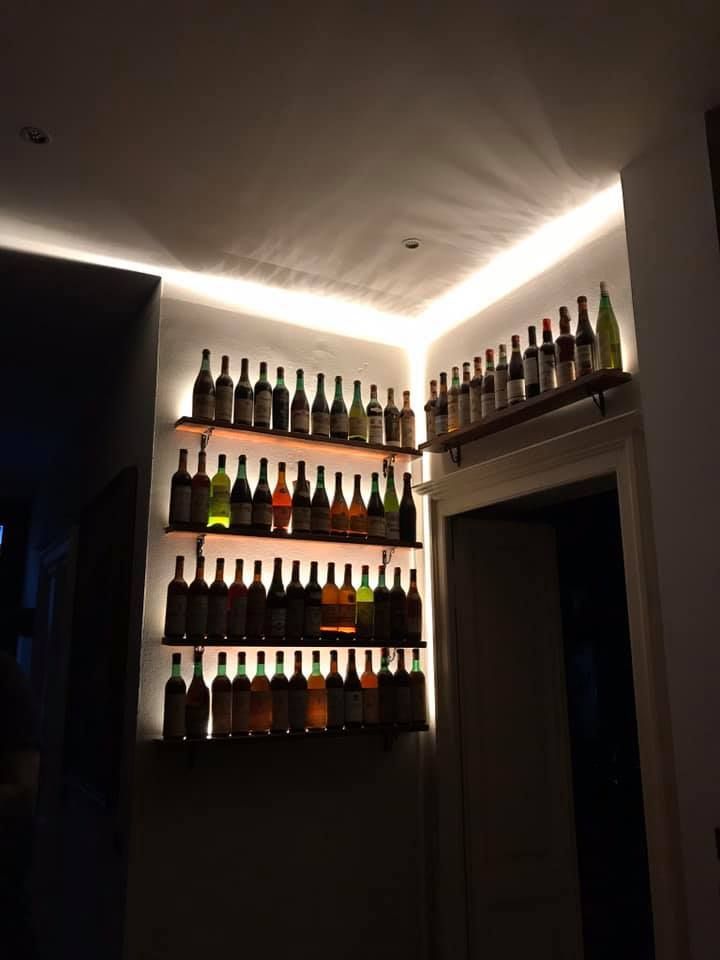 Scaffali con file di bottiglie di liquore illuminate da lampade al neon in un angolo scarsamente illuminato.