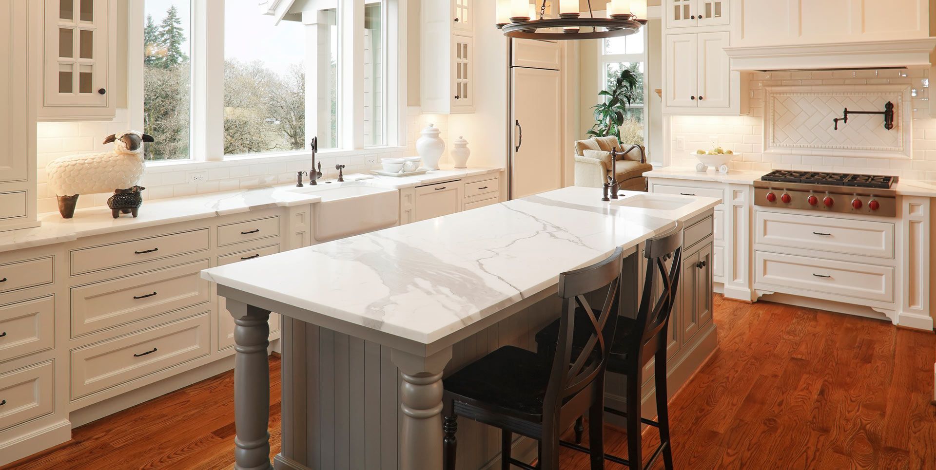 A kitchen with white cabinets and hardwood floors and a large island in the middle.