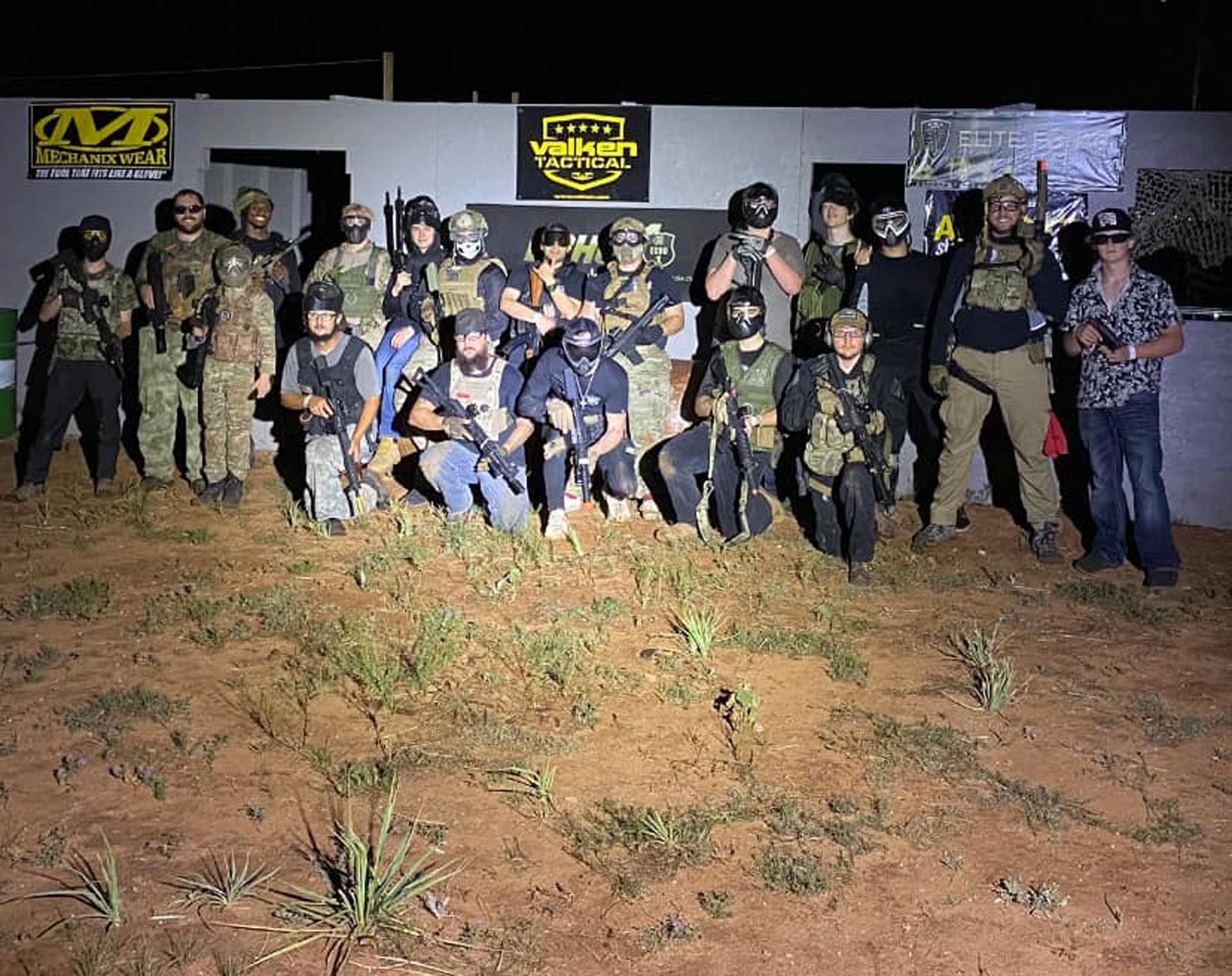 A group of airsoft players are posing for a picture in front of a building
