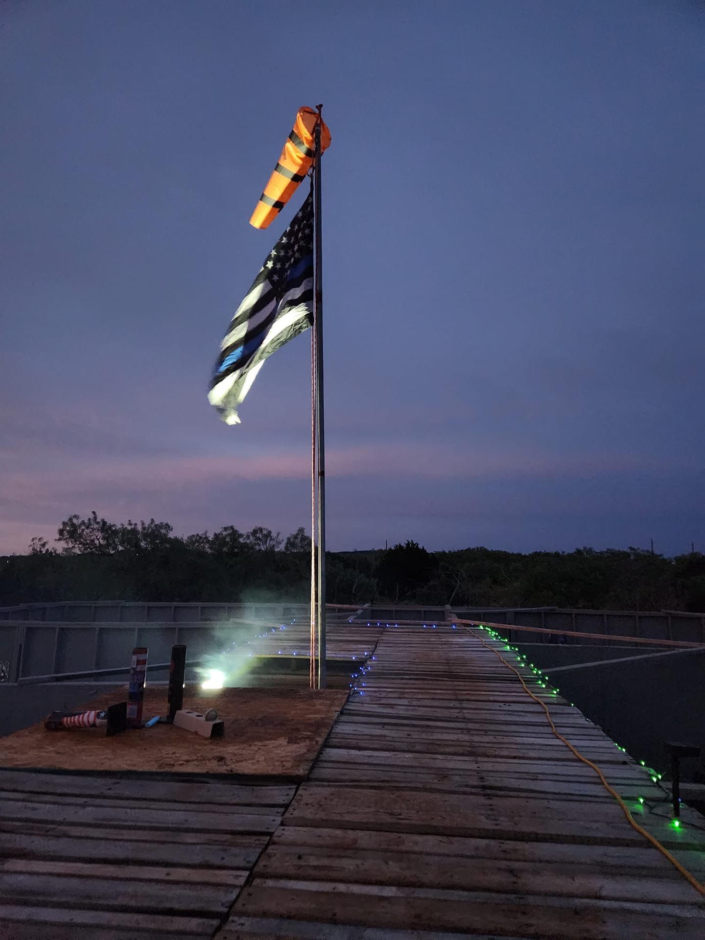 An American flag is flying on top of a wooden dock at night