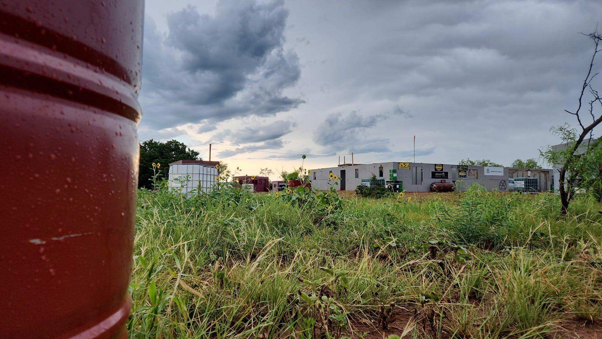 A red barrel is sitting in the middle of a grassy field