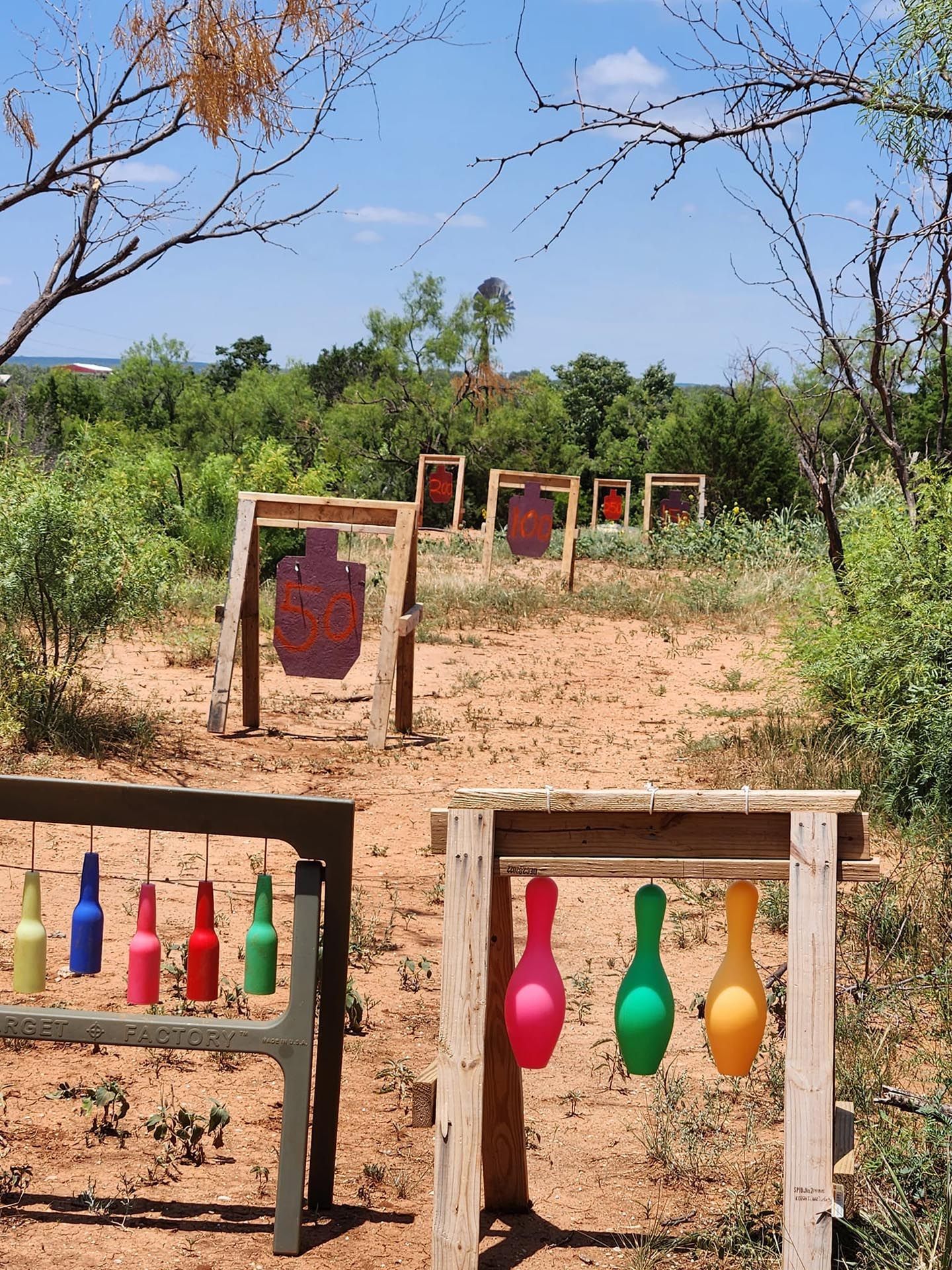 A bunch of balloons are hanging from a wooden stand in a field
