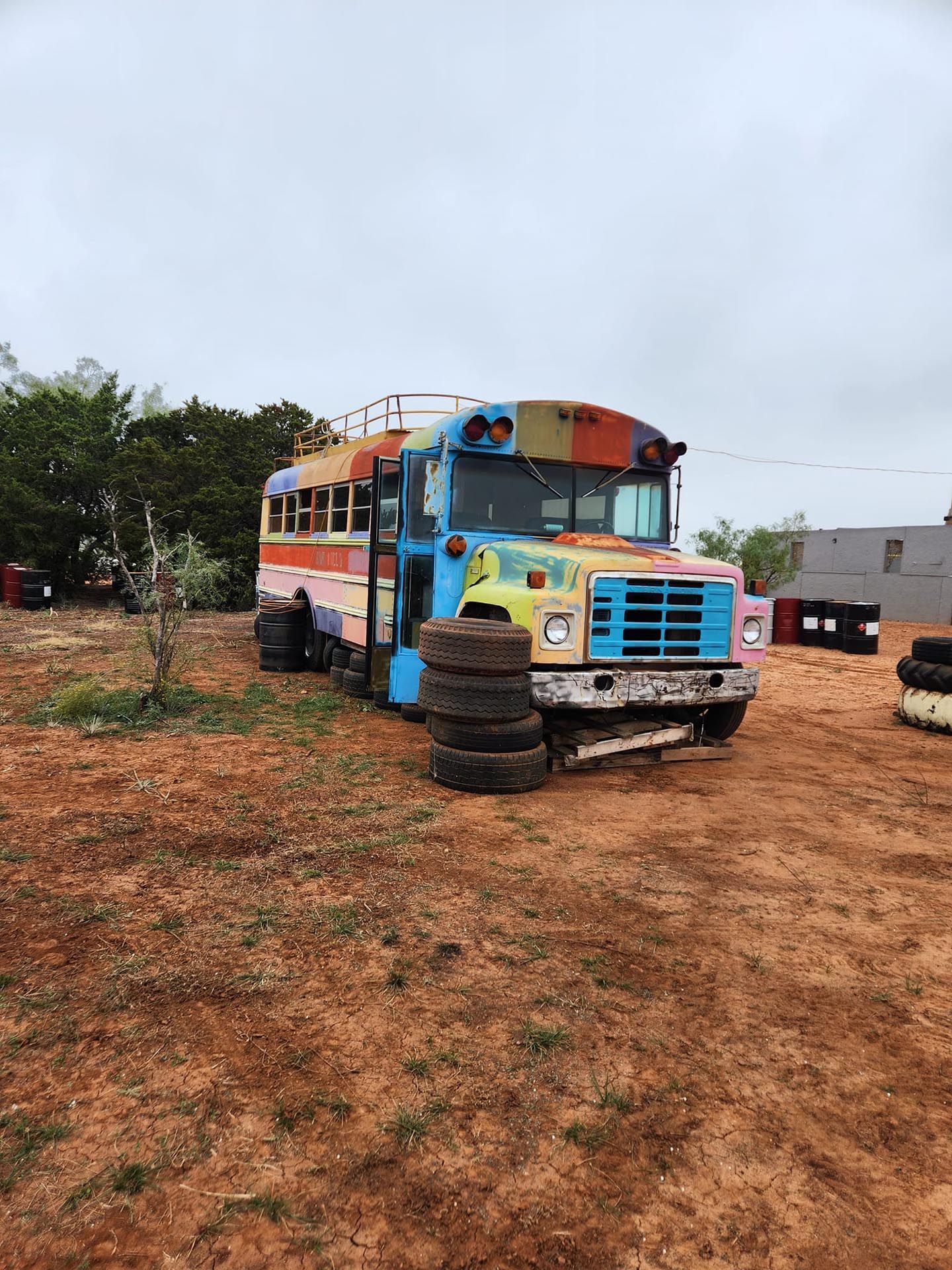 A colorful school bus is parked in a dirt field