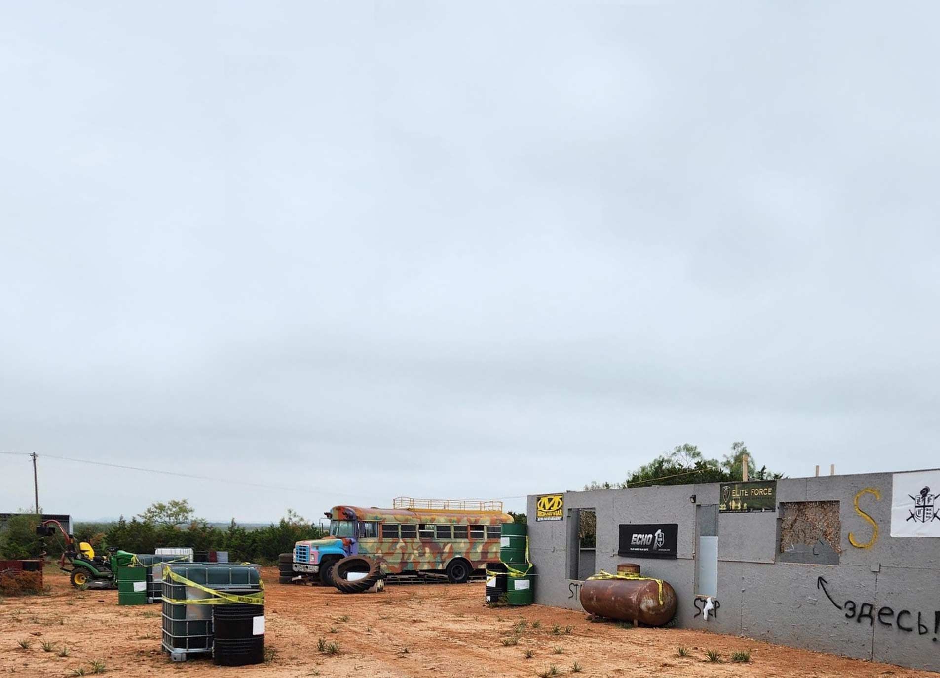 A school bus is parked in a dirt field next to a building