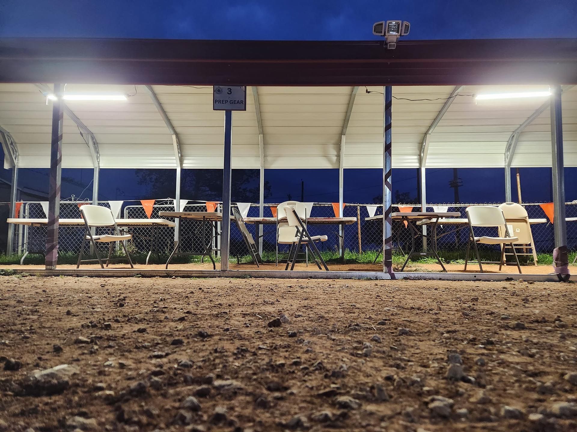A row of tables and chairs under a tent at night