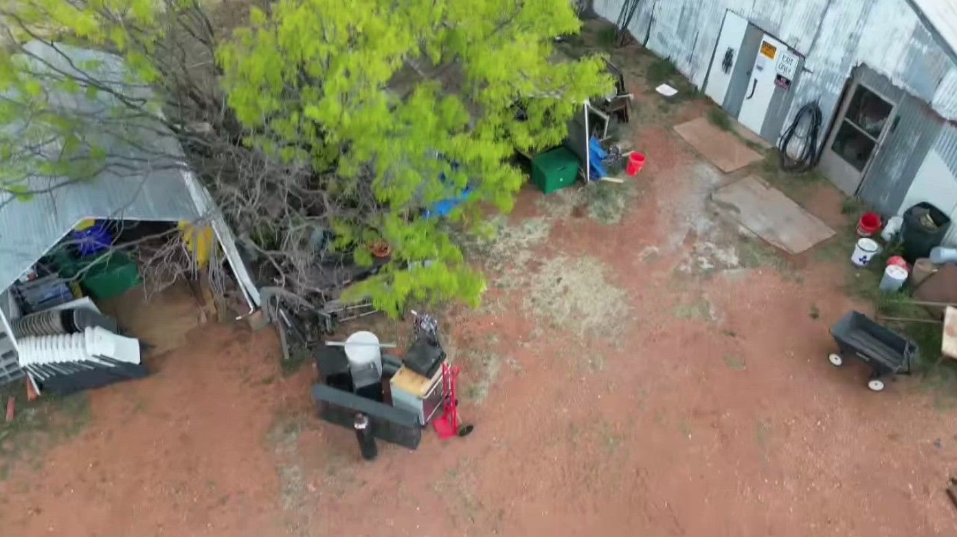 An aerial view of a man carrying a couch in a backyard