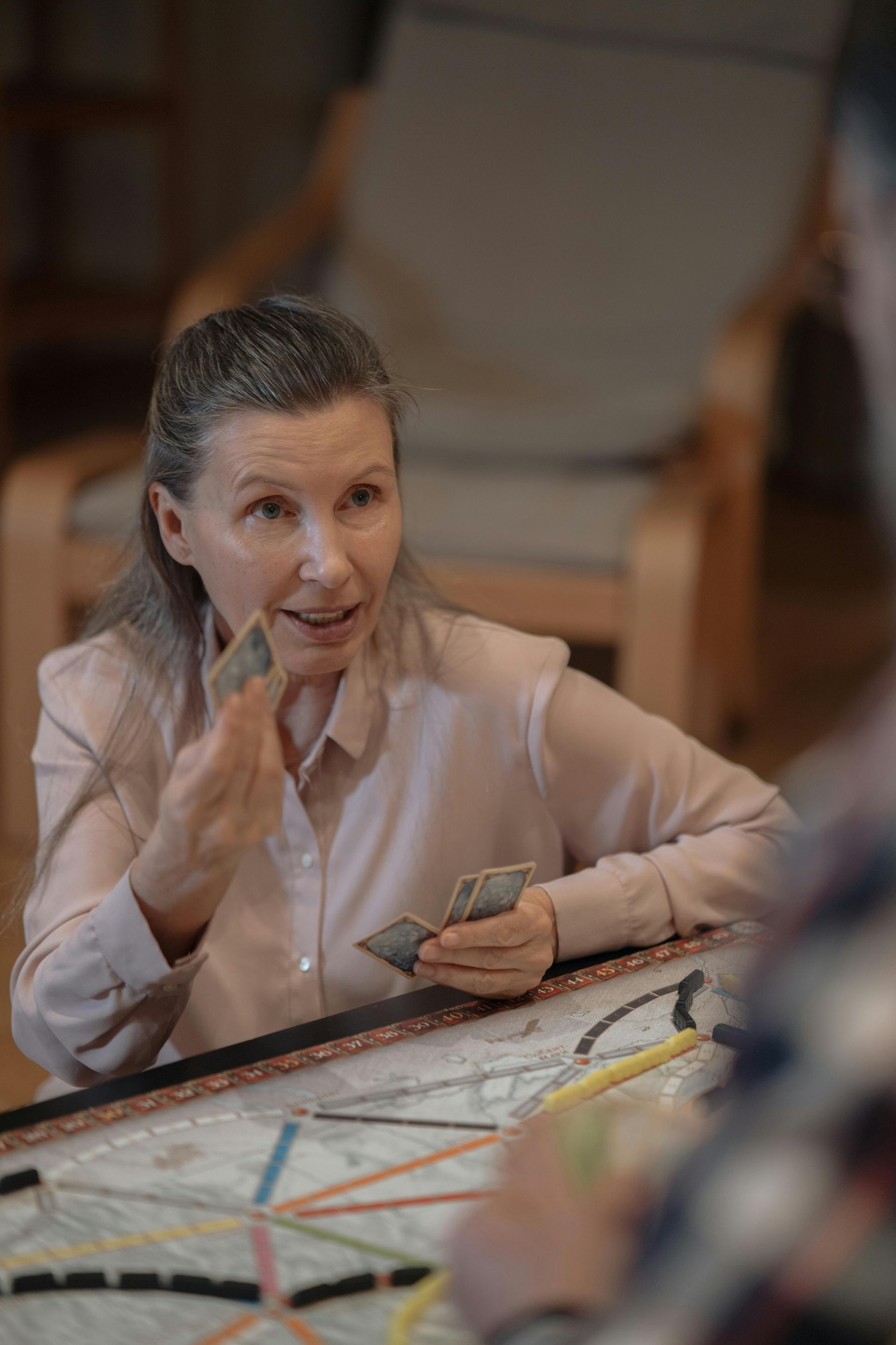 Une femme est assise à une table et joue à un jeu de société avec un homme.