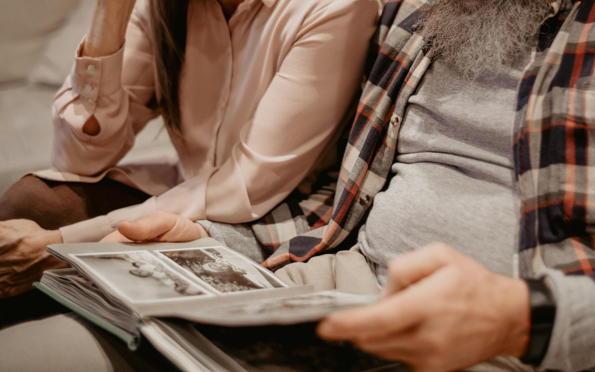Un homme et une femme sont assis sur un canapé et regardent un album photo.