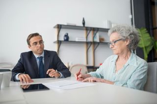 Un homme et une femme sont assis à une table et signent un document.