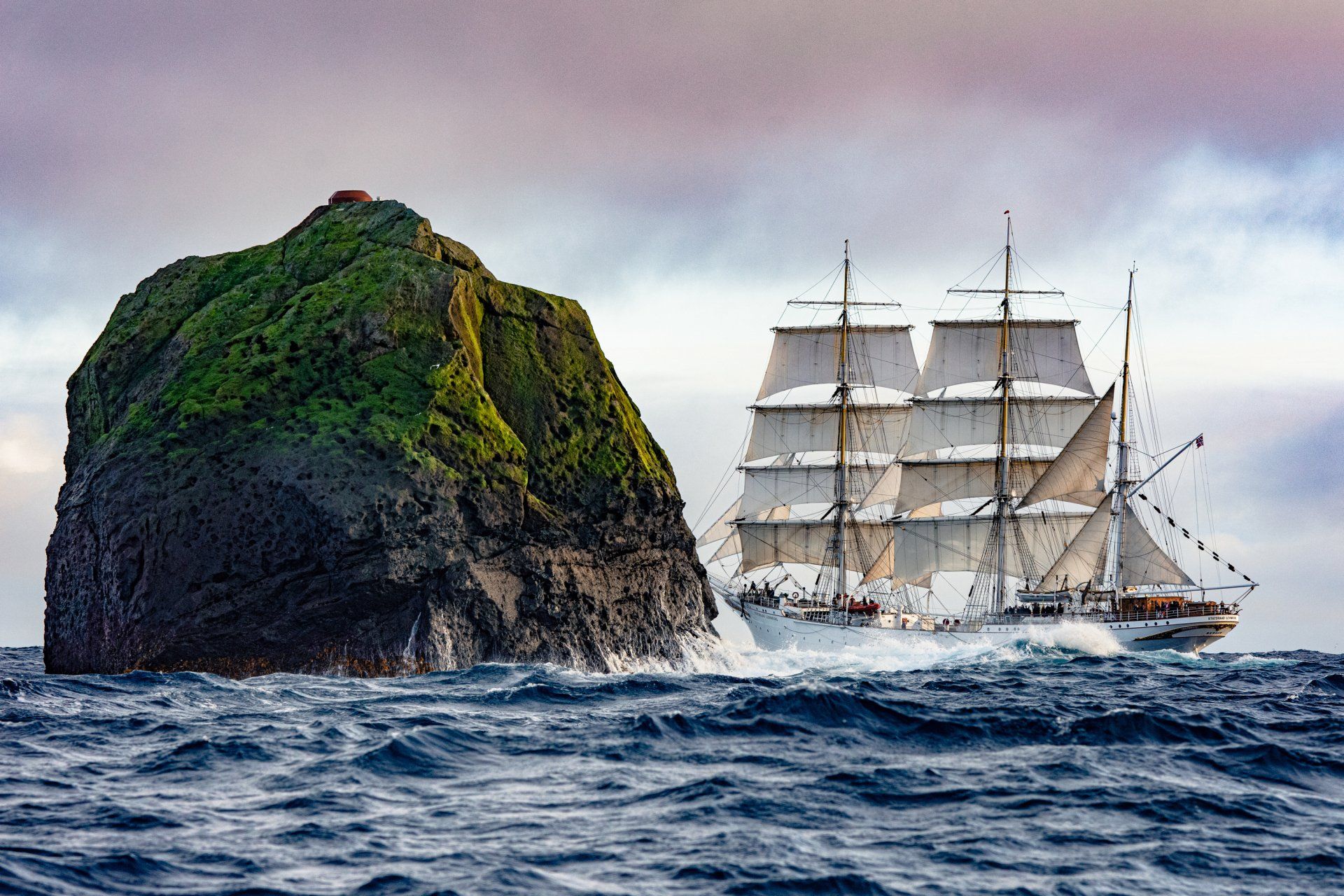 En sejlbåd sejler i havet ved siden af ​​en stor sten.