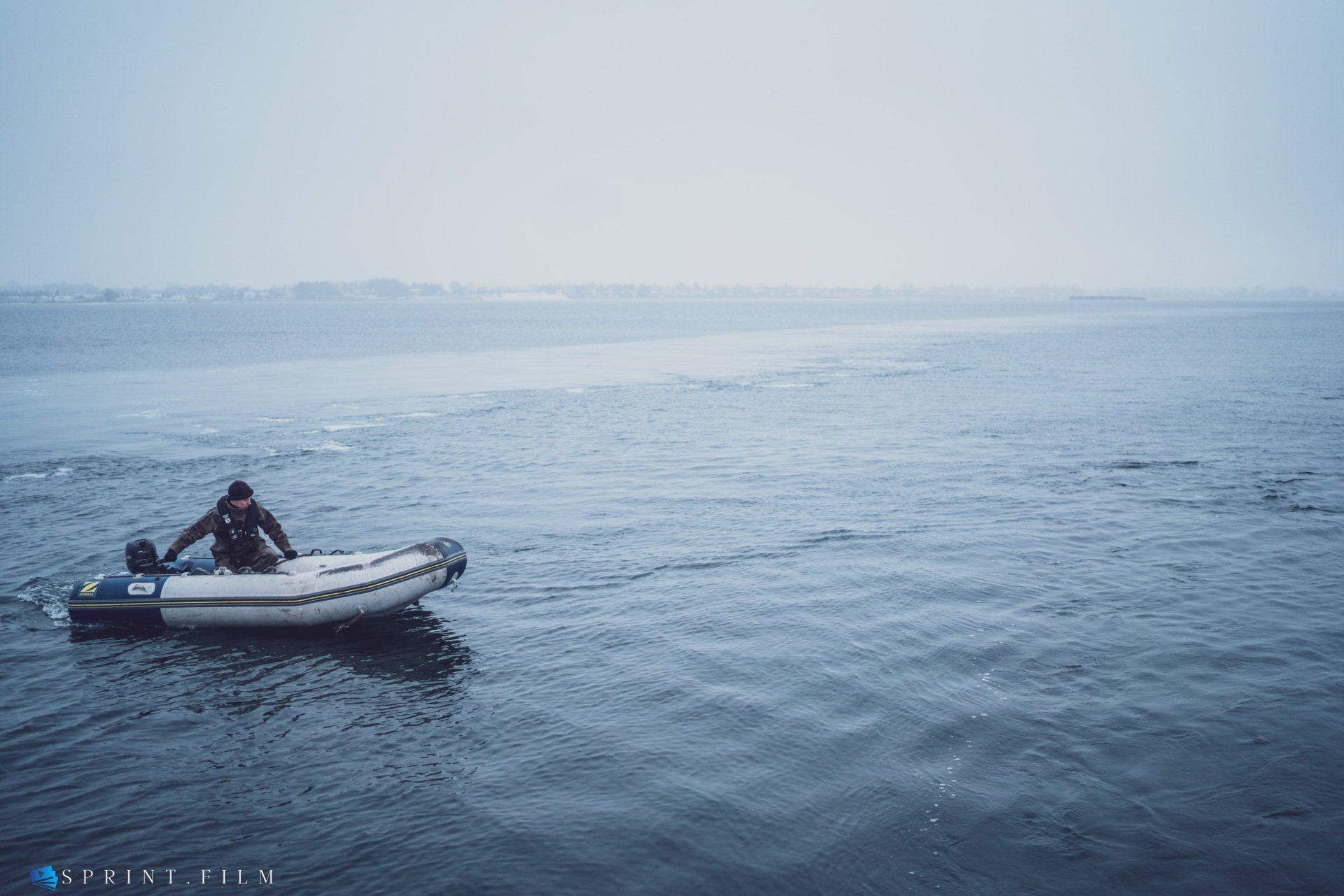 En mand sidder i en lille båd midt på havet.