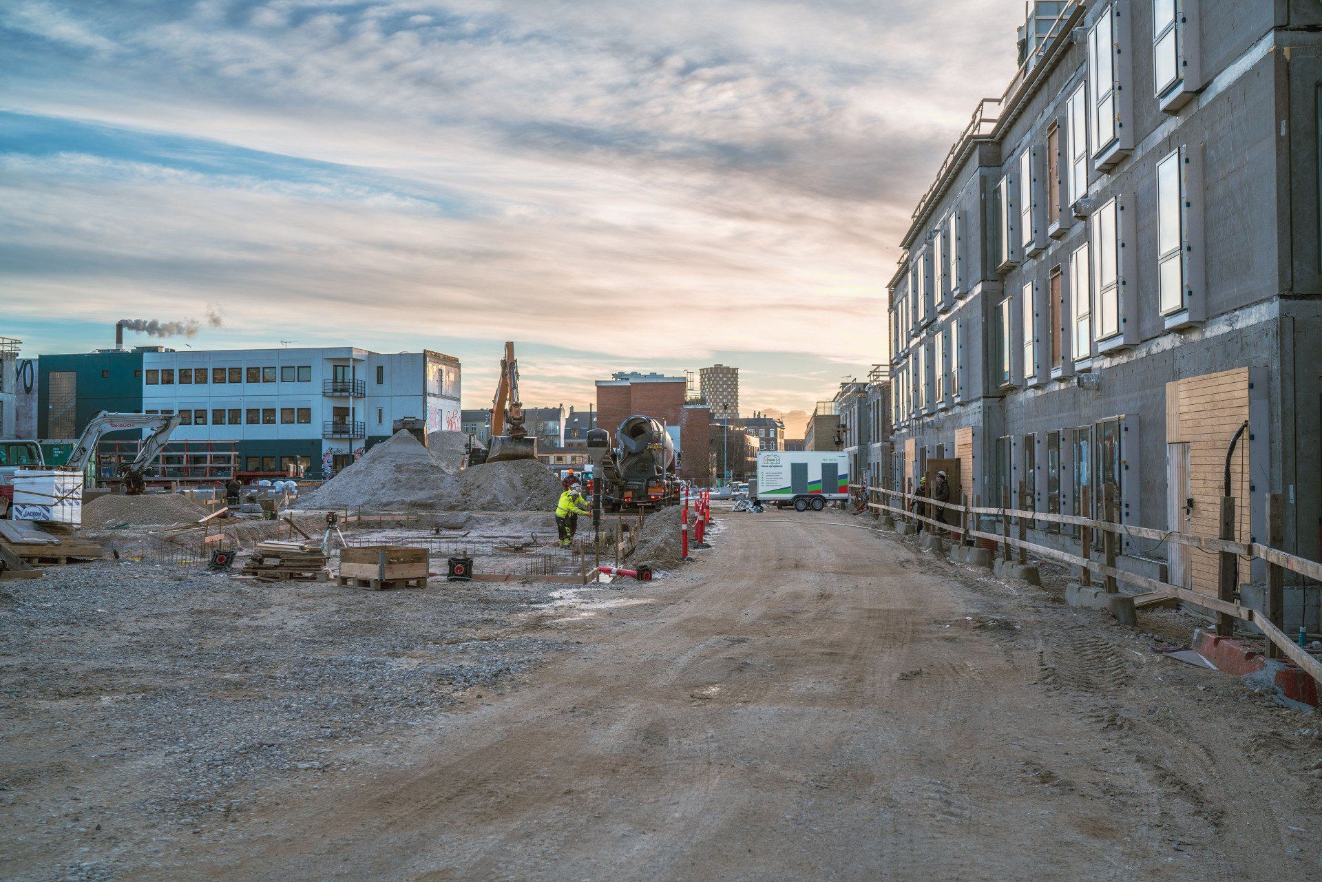En byggeplads med en masse snavs og bygninger i baggrunden.