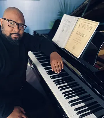 A man is sitting at a piano with a book on it that says schubert A man is sitting at a piano with a book on it that says schubert