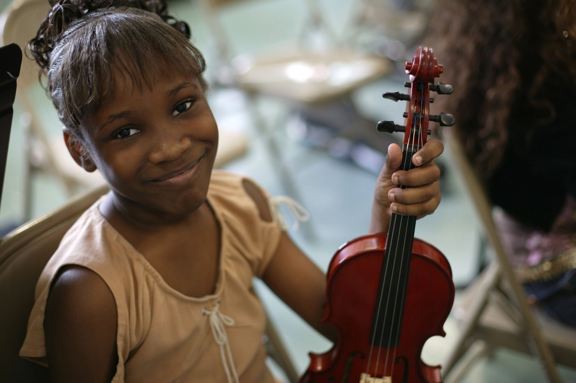 A young girl is holding a violin and smiling