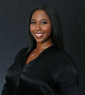 A woman in a black shirt and necklace is smiling for the camera.