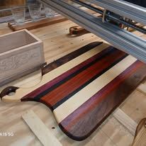 Wooden cutting board with colorful stripes, being worked on near a machine.