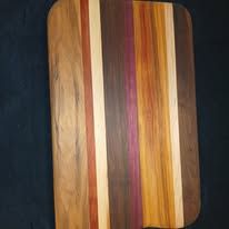 Wooden cutting board with vertical stripes of various wood tones and colors.