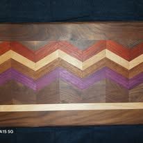Wooden cutting board with a chevron pattern of various colors.