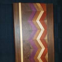 Wooden cutting board with a chevron pattern of purple, orange, and tan wood.