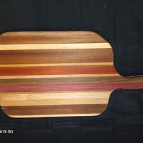 Wooden pizza peel with horizontal stripes in various shades of brown, orange, and purple.
