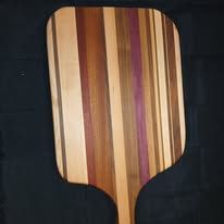 Wooden pizza peel with vertical stripes of light and dark wood.