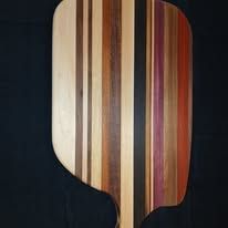 Wooden pizza peel with vertical stripes of various colors.