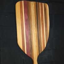Wooden pizza peel with vertical stripes of various wood tones.