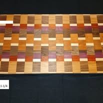 Wooden cutting board with a checkerboard pattern of various wood tones.