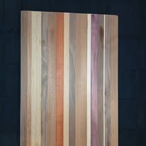 Wooden cutting board with vertical stripes of various colors.