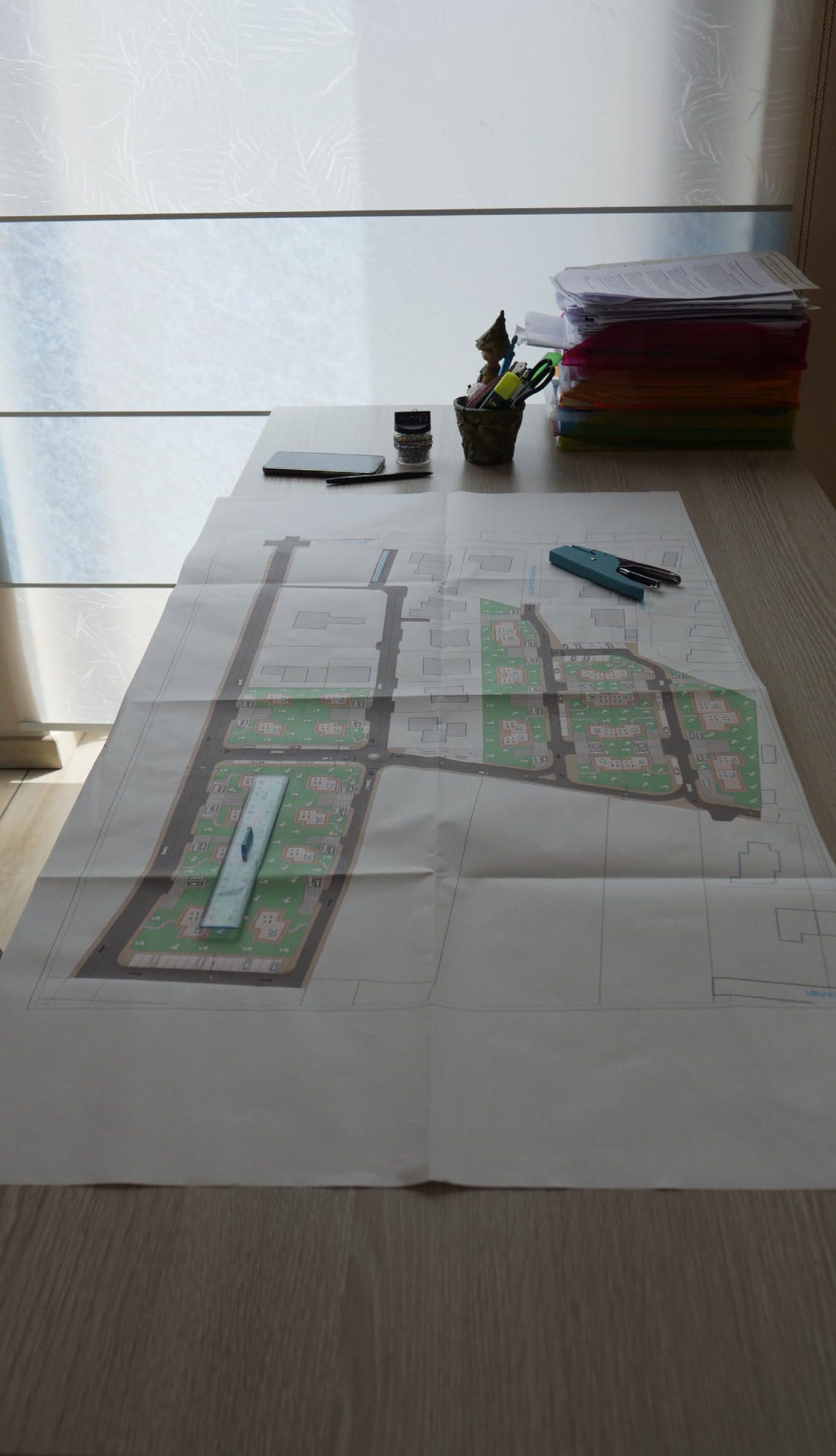 Una mappa è appoggiata su un tavolo accanto a una pila di fogli.